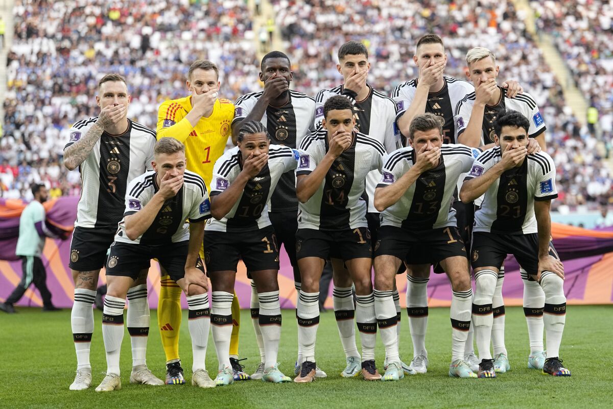 German players covered their mouths with their hands in a photo before the game against Japan, protesting a ban on rainbow armbands